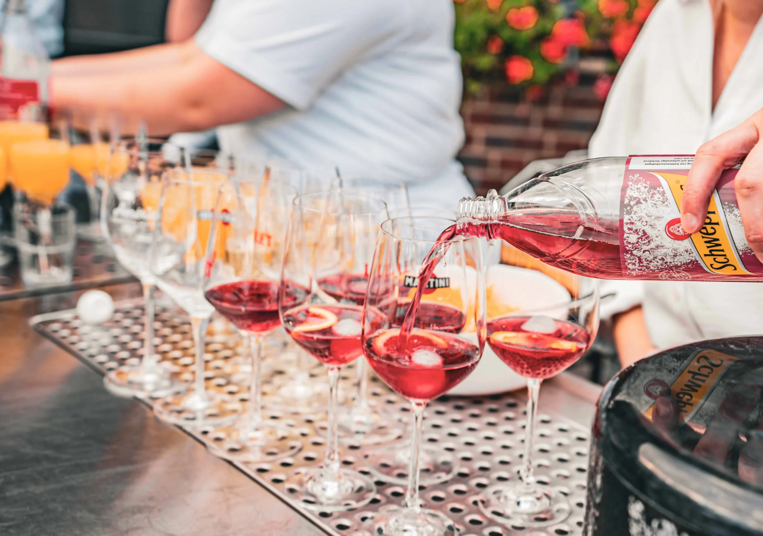 Mehrere Gläser mit roten Getränken, Eiswürfeln und Zitronenscheiben.