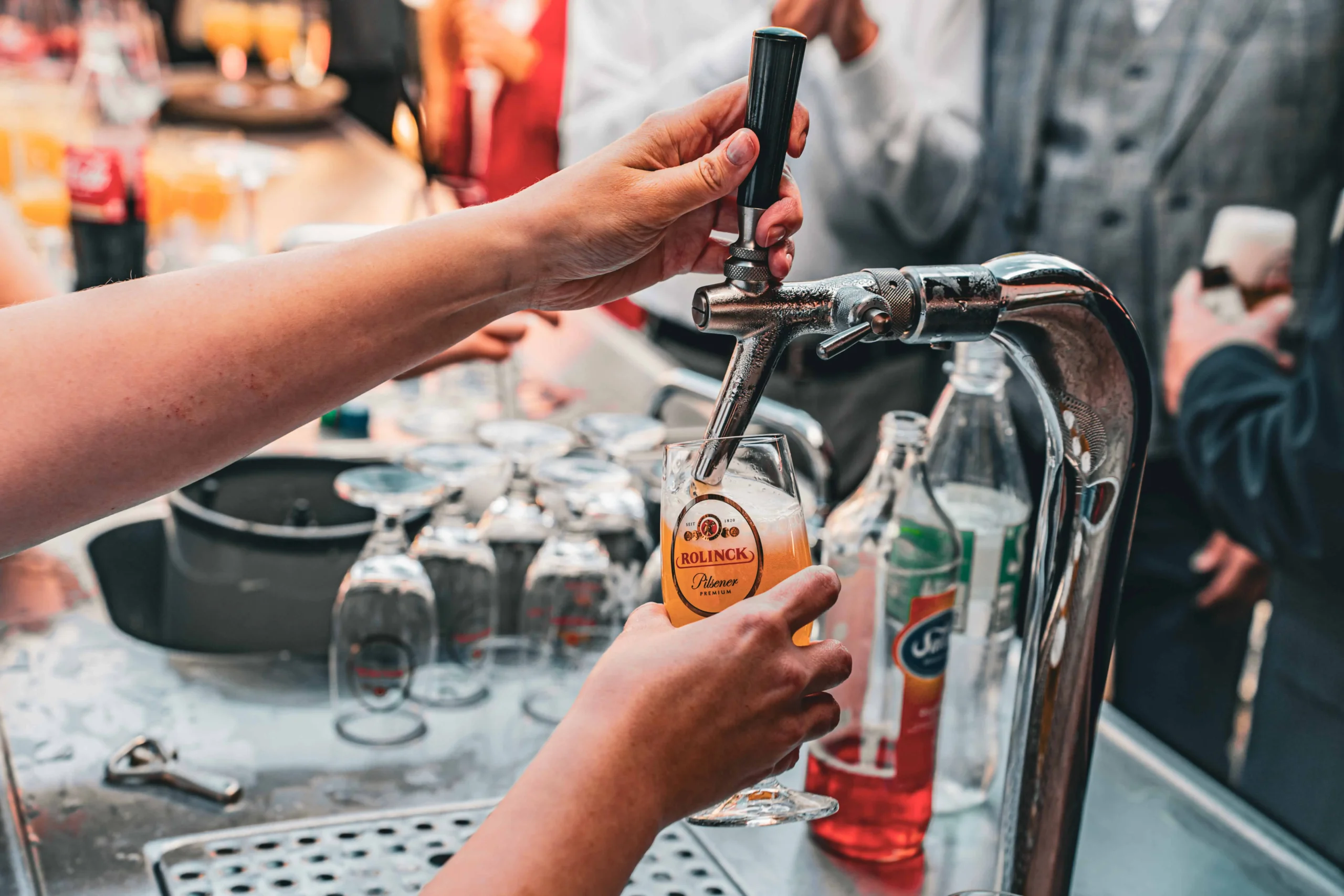 Hand zapft ein Glas Bier an einem Zapfhahn.