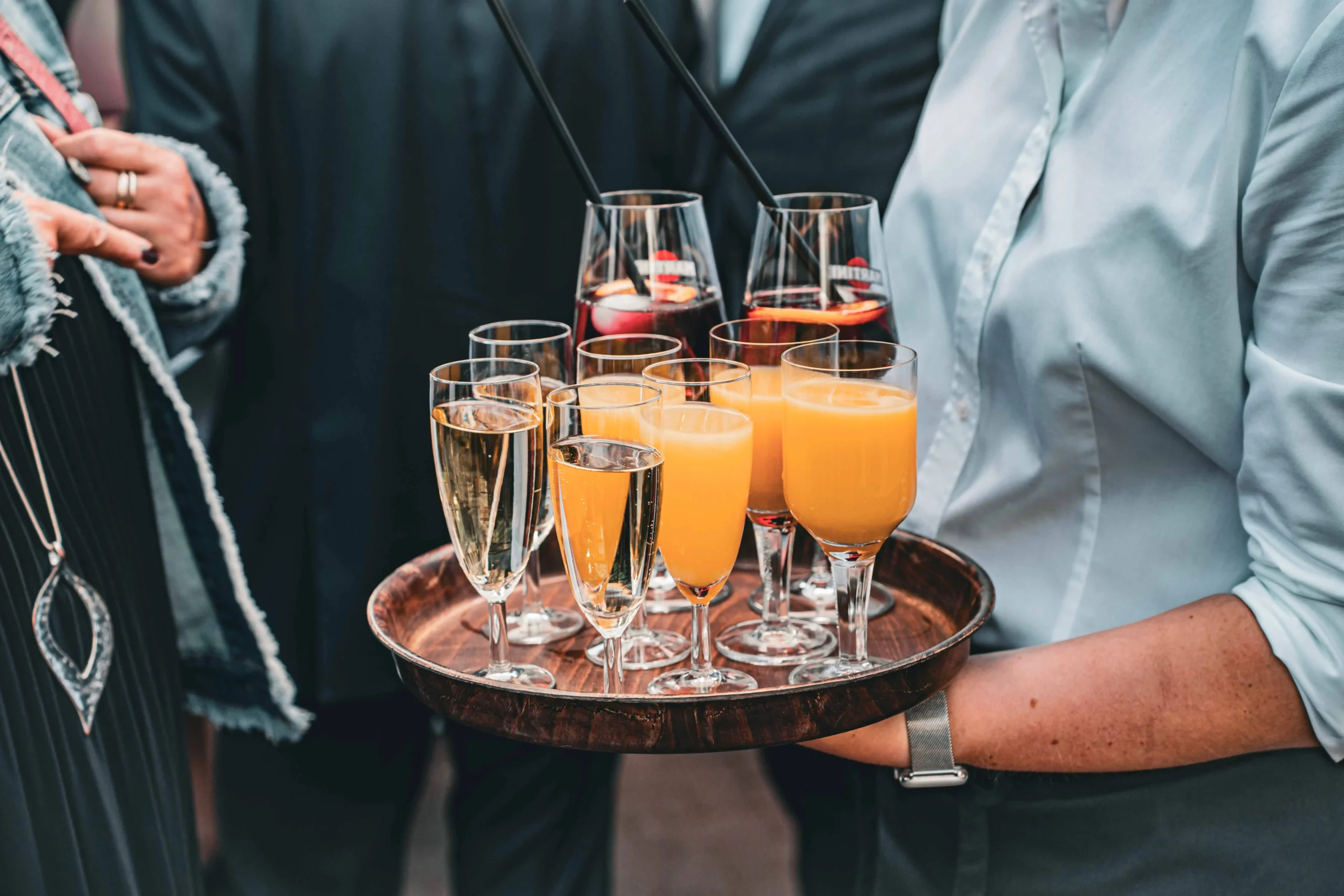 Kellner trägt Tablett mit Gläsern voller Sekt und Orangensaft.