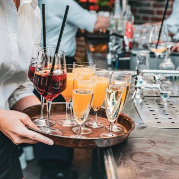 Kellner trägt Tablett mit Gläsern voller Sekt und Orangensaft.