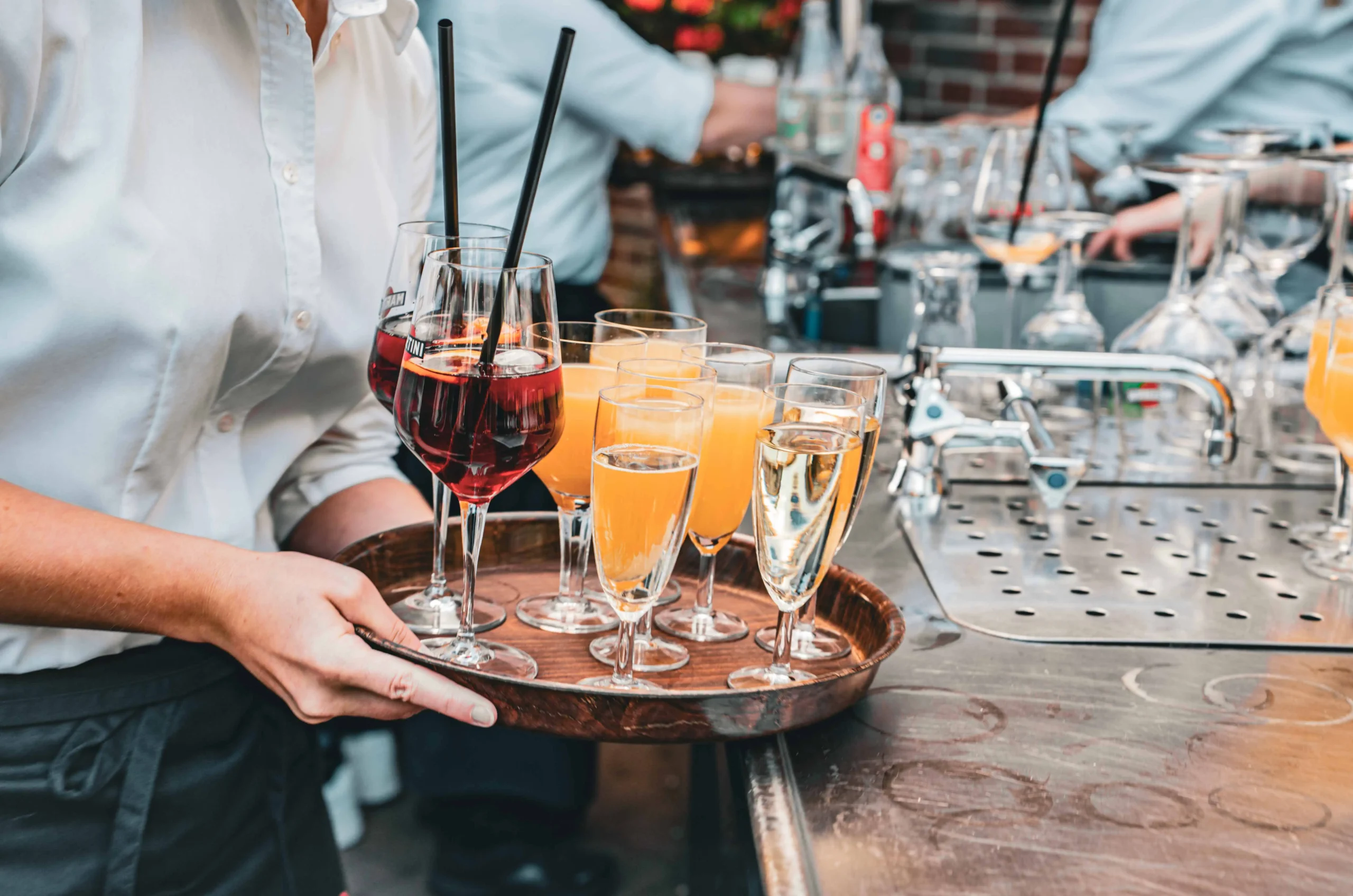 Kellner trägt Tablett mit Gläsern voller Sekt und Orangensaft.