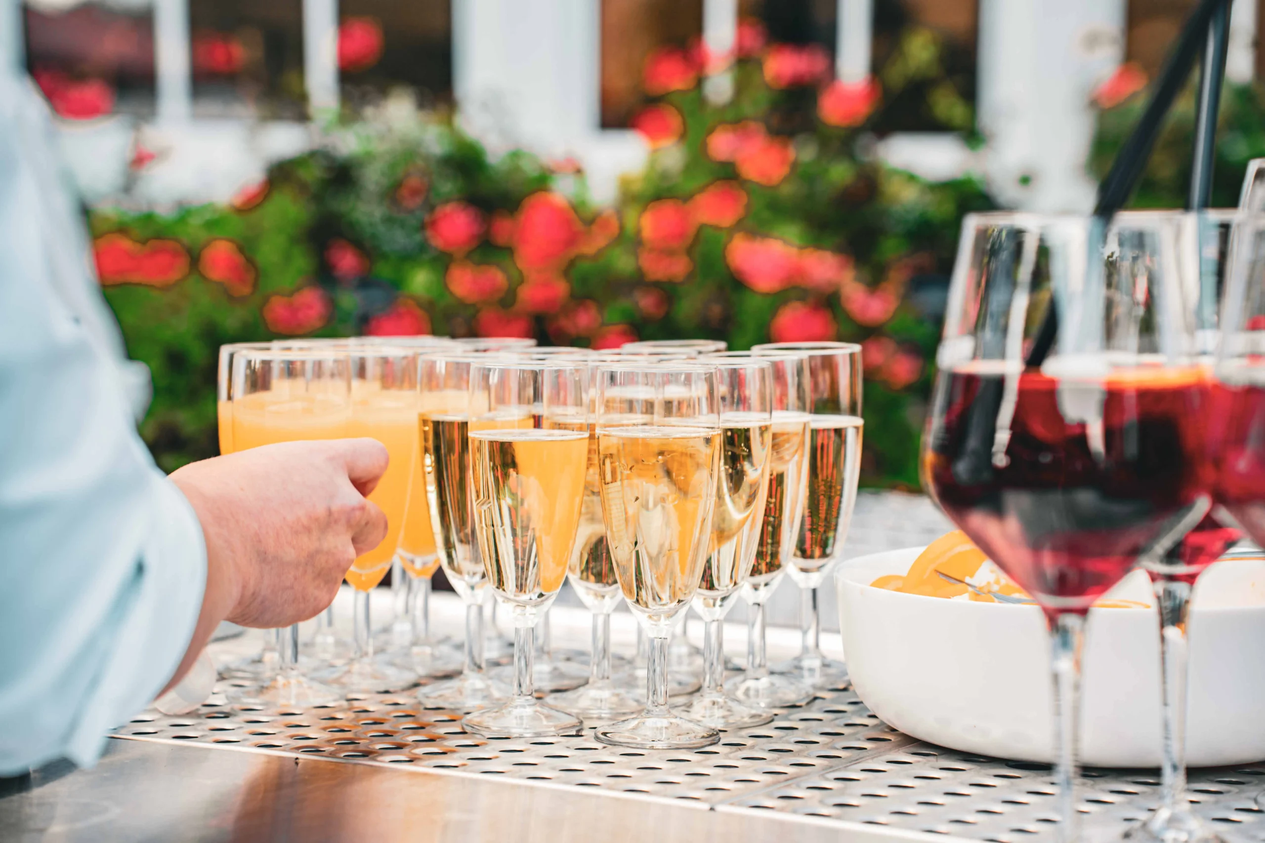 Gläser mit Aperitifs auf der Theke, im Hintergrund blühende Pflanzen.