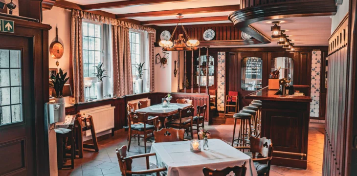 Gastraum mit eingedeckten Tischen und Bar.