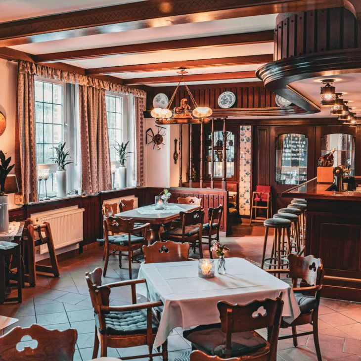 Gastraum mit eingedeckten Tischen und Bar.