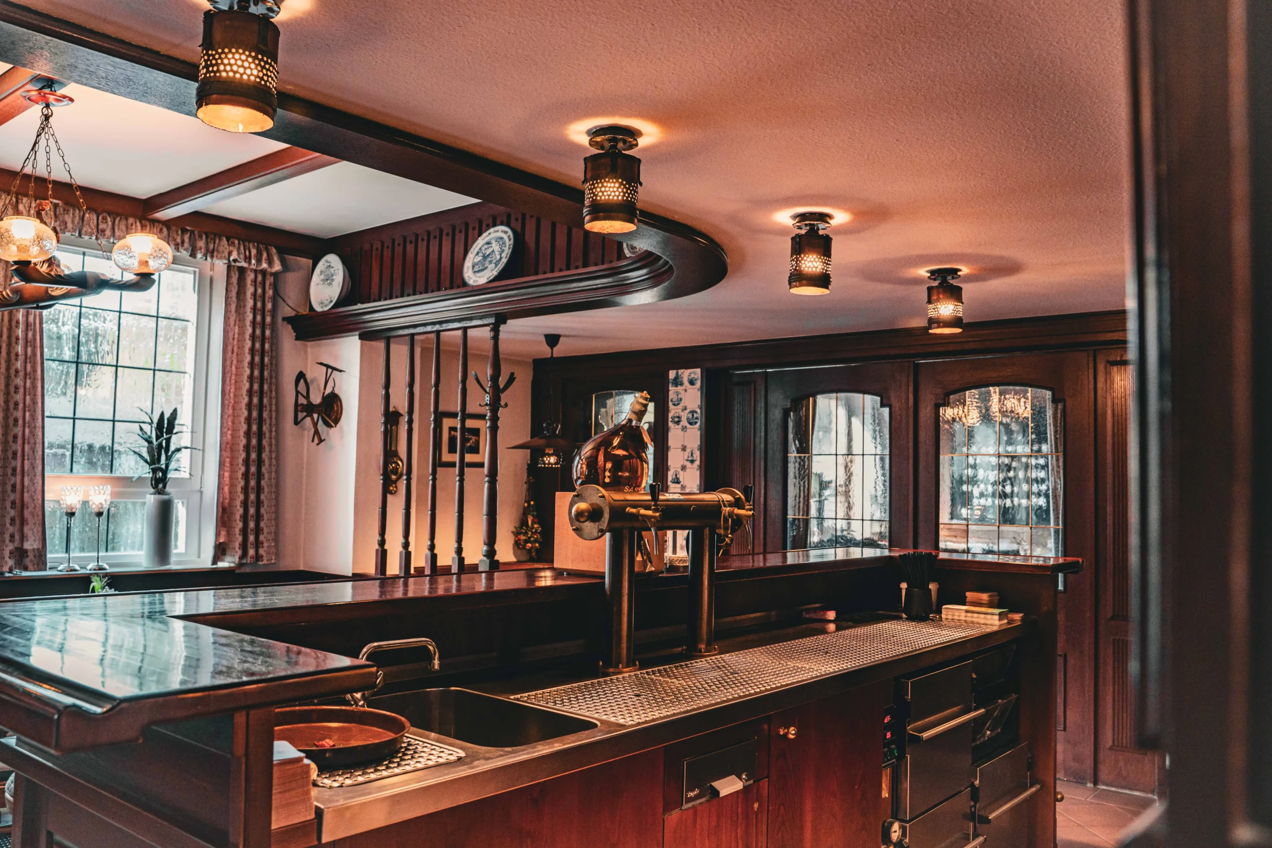 Gastraum mit Holztheke, Tischen und Lampen.