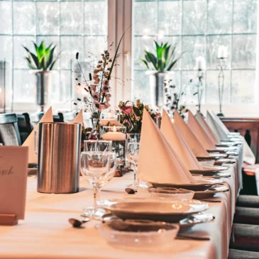 Lang gedeckter Tisch mit Servietten und Gläsern.