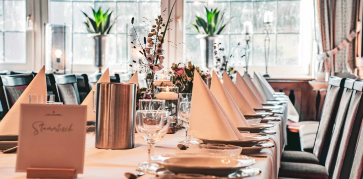 Lang gedeckter Tisch mit Servietten und Gläsern.