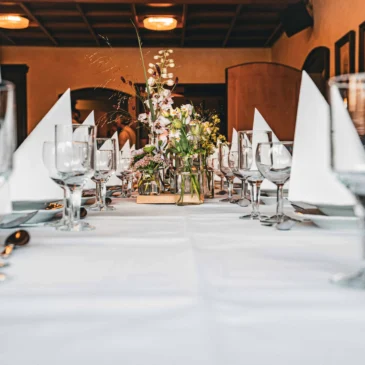 Nahaufnahme einer gedeckten Festtafel mit Servietten und Blumen.