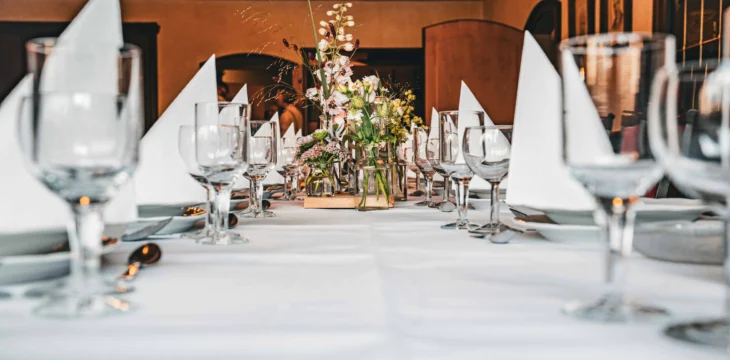 Nahaufnahme einer gedeckten Festtafel mit Servietten und Blumen.