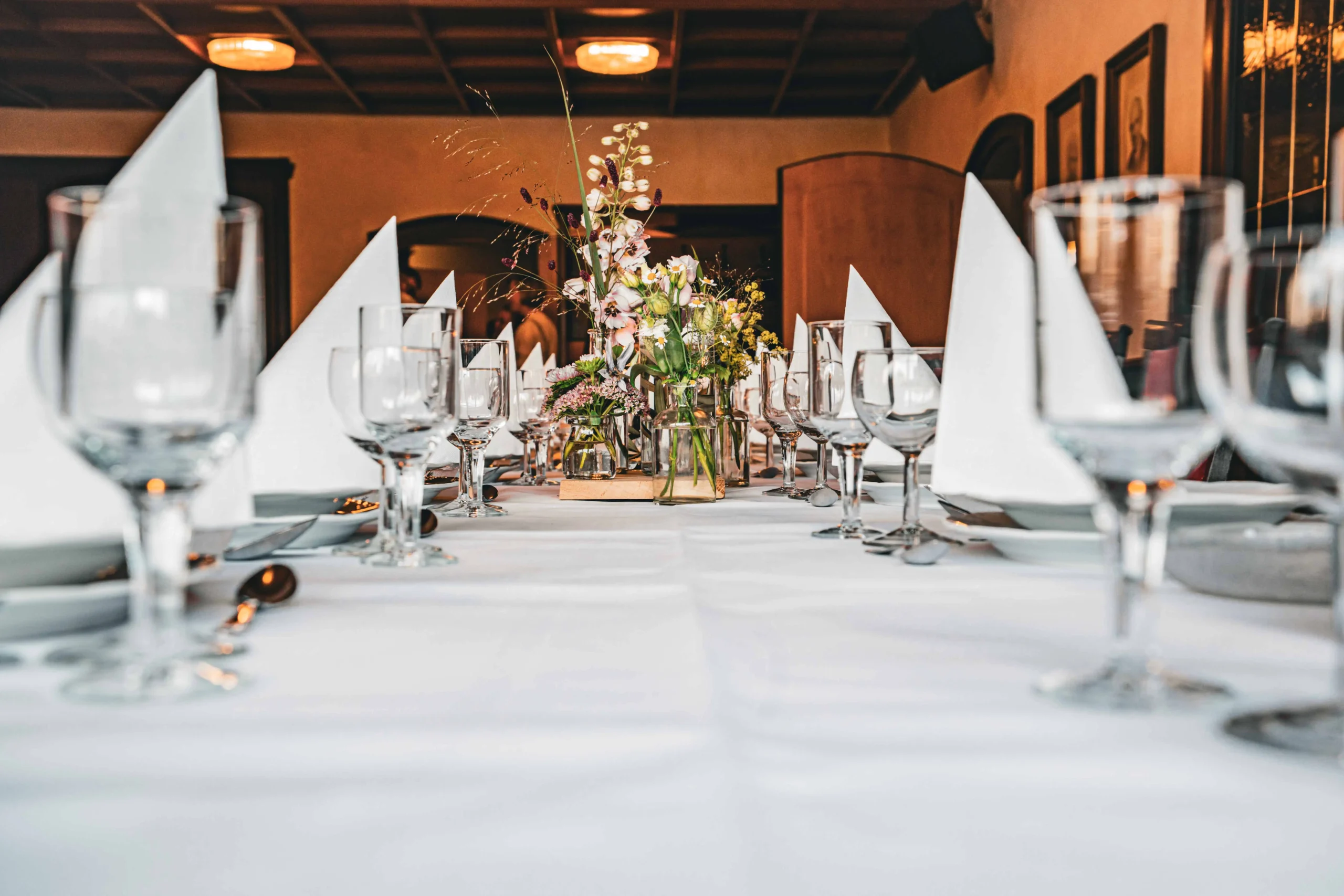Nahaufnahme einer gedeckten Festtafel mit Servietten und Blumen.